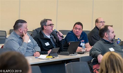 Man holds microhphone speaking to Symposium leader.